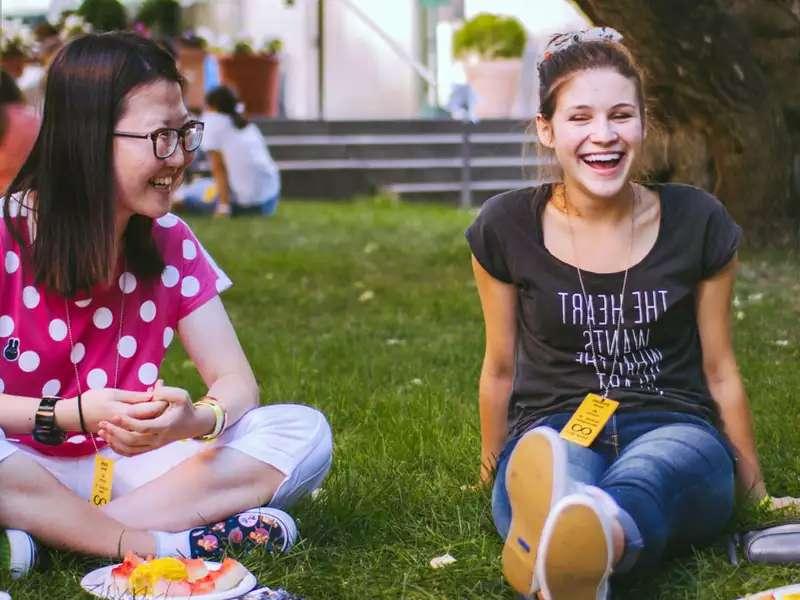 2 students on the grass, laughing